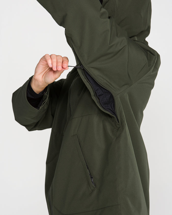 A person wearing the Volcom Women’s Steele Insulated Jacket in dark green unzips an underarm vent, highlighting the jacket’s ventilation feature. Only their upper body and part of one arm are visible.