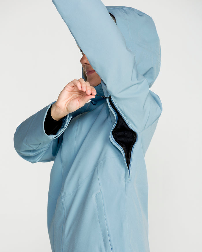 A person wearing the Volcom Women’s Stoney Shadow Insulated Jacket in light blue raises an arm to reveal the underarm zipper vent being opened, set against a plain white background.