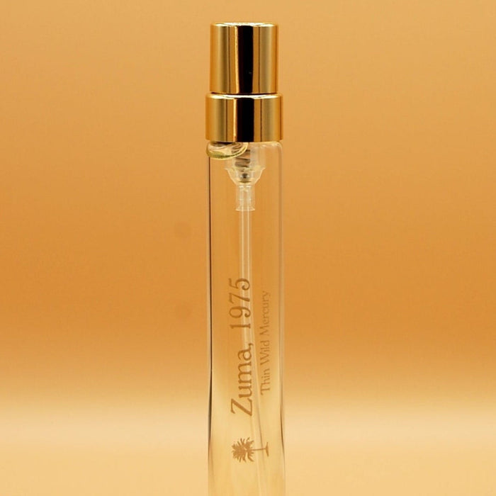 A clear glass 8ml travel sprayer with a gold cap, labeled 'Zuma, 1975'